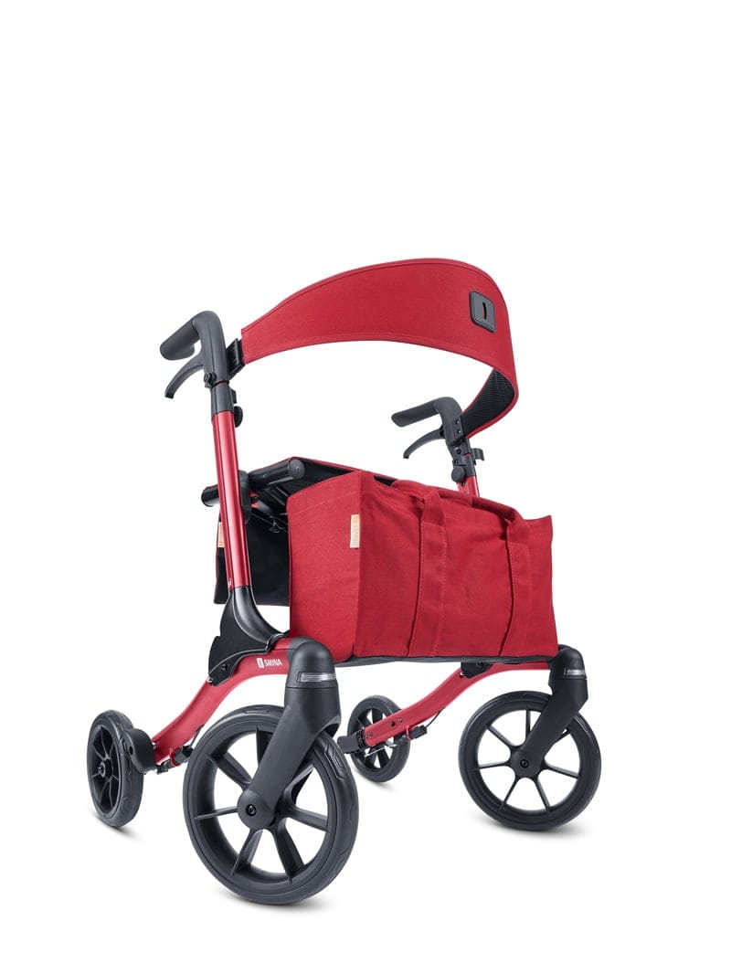 Front-/Seitenansicht eines roten Reise-Rollator, Modell Resi von Smina, mit Rückengurt, Tasche und Softbereifung.