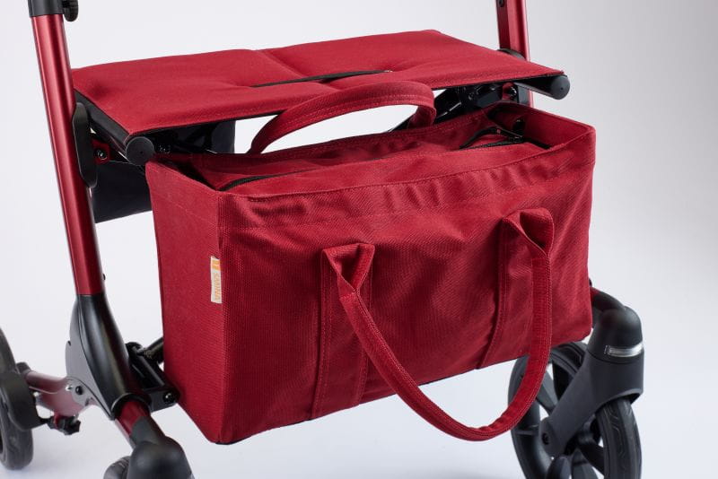 Frontsicht am SMINA Resi Rollator, von der gepolsterten Sitzfläche und Einkaufstasche in rot.